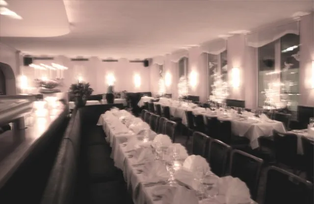 Lange, weiß gedeckte Tafel im Restaurant bei Kerzenlicht